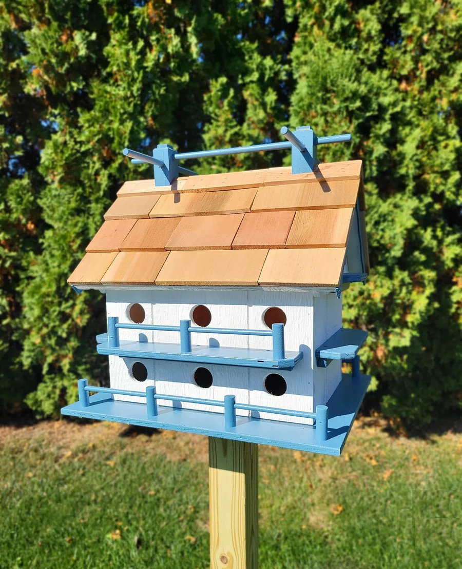 Handcrafted bird and house design featuring a two-story white birdhouse with blue perches, a cedar shake roof, and 14 round entrance holes for purple martins.