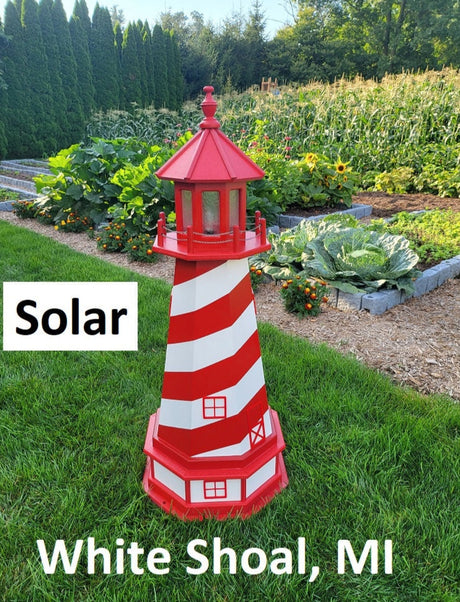May include: A red and white striped lighthouse with a solar light. The lighthouse is in a garden setting with green grass and plants. The text 'Solar' and 'White Shoal, MI' are visible in the image.
