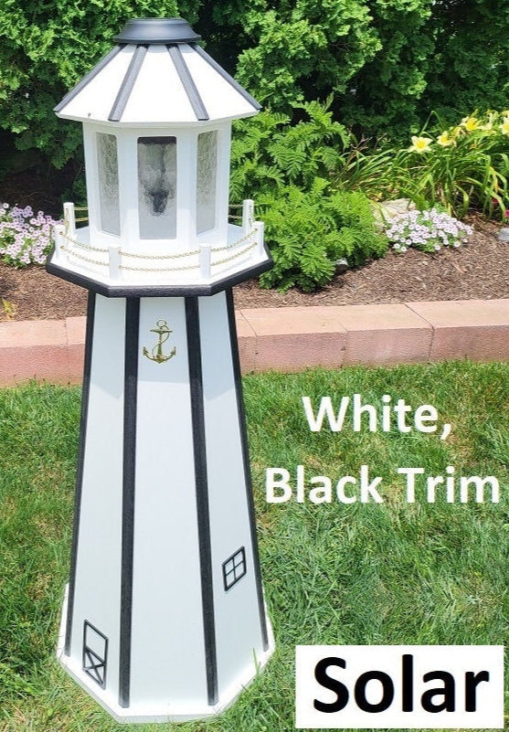 May include: White solar powered lighthouse with black trim. The lighthouse has a gold anchor on the front and two small windows. The text 'White, Black Trim' and 'Solar' is visible below the lighthouse.