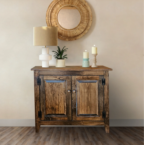 Rustic cabinets featuring solid wood two-door design with dark iron hardware, weathered oak finish, fully assembled with decorative staging including modern lamp, mirror, and candle holders